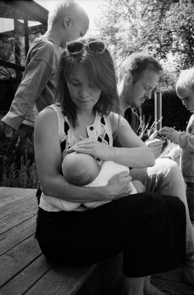 une mère qui allaite son bébé avec sa famille autour d'elle pendant une séance photo famille et nouveau-né dans le Bas-Rhin