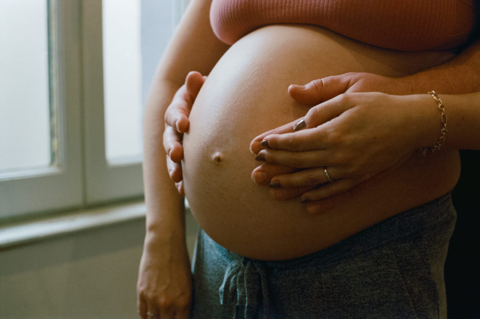 Ventre rond de grossesse avec les mains de la maman et du papa