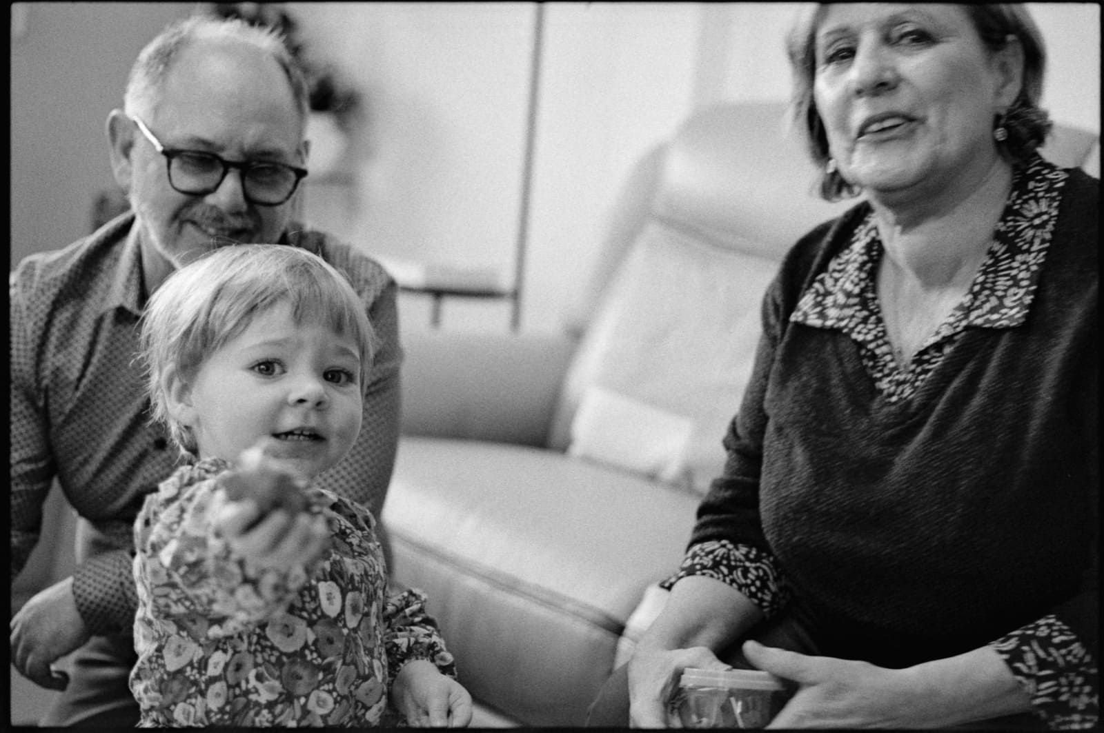 une petite fille avec ses grands-parents dans leur salon