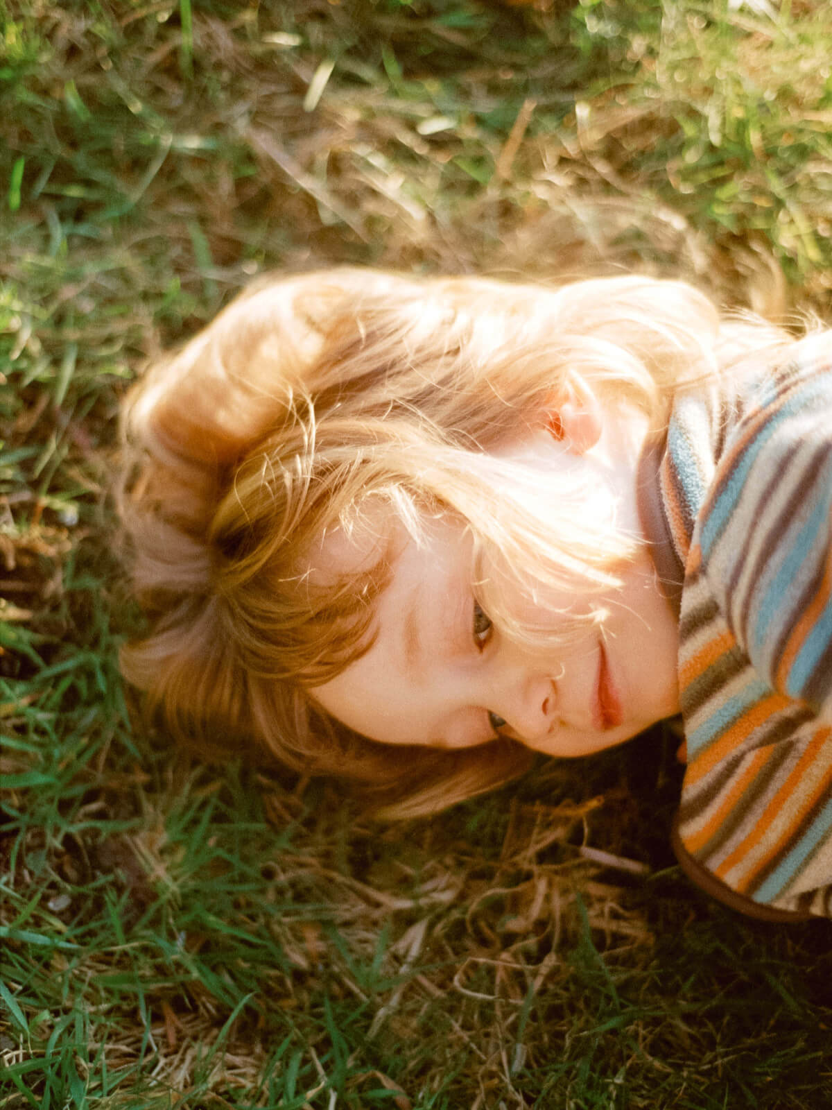 un enfant souriant, la tête dans l'herbe