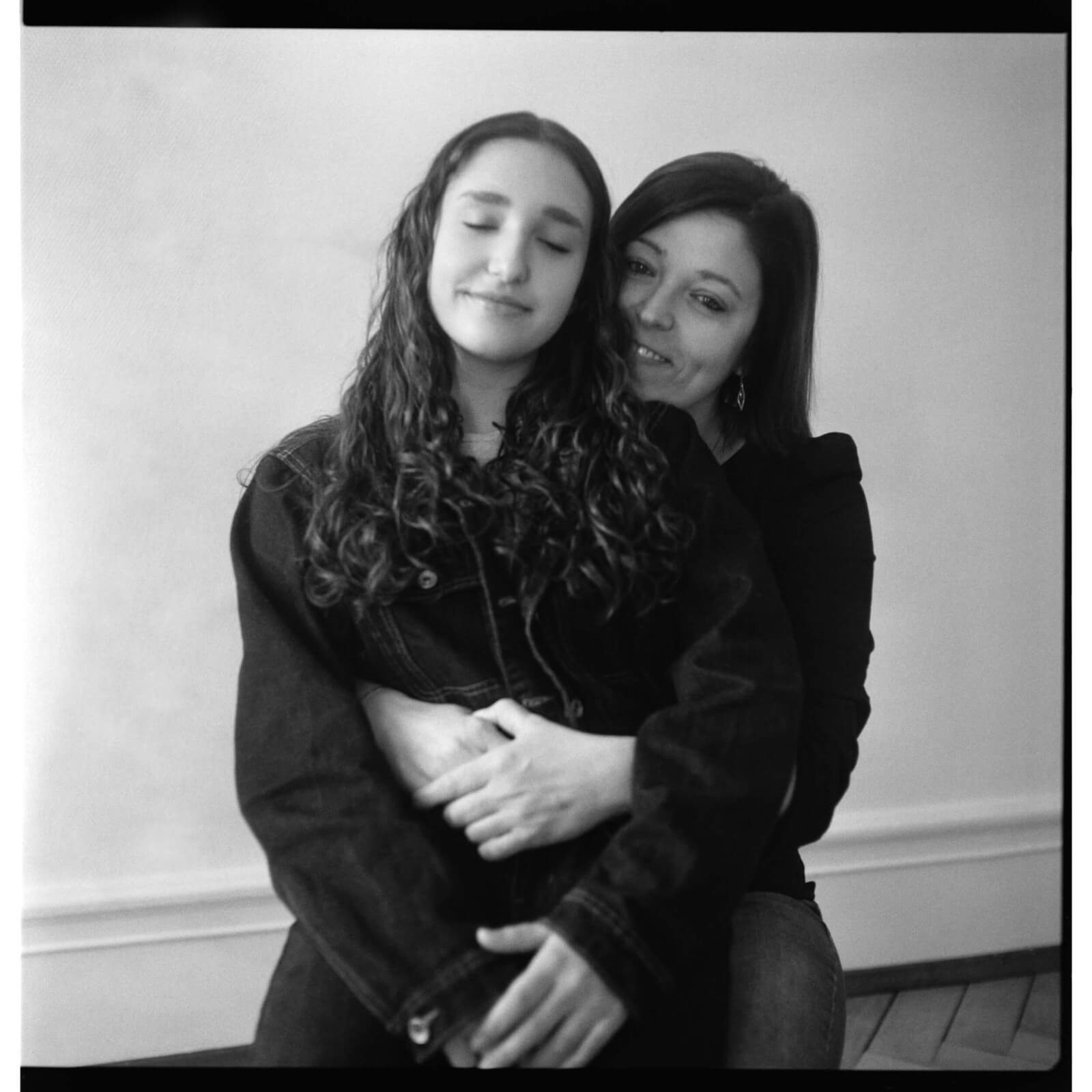 une maman souriante et sa fille ado dans les bras pendant une séance photo Fête des mères