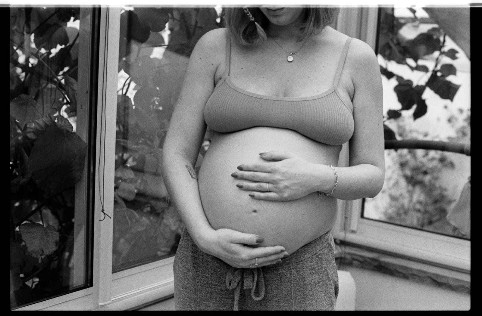 femme enceinte, les mains sur le ventre, devant une fenêtre